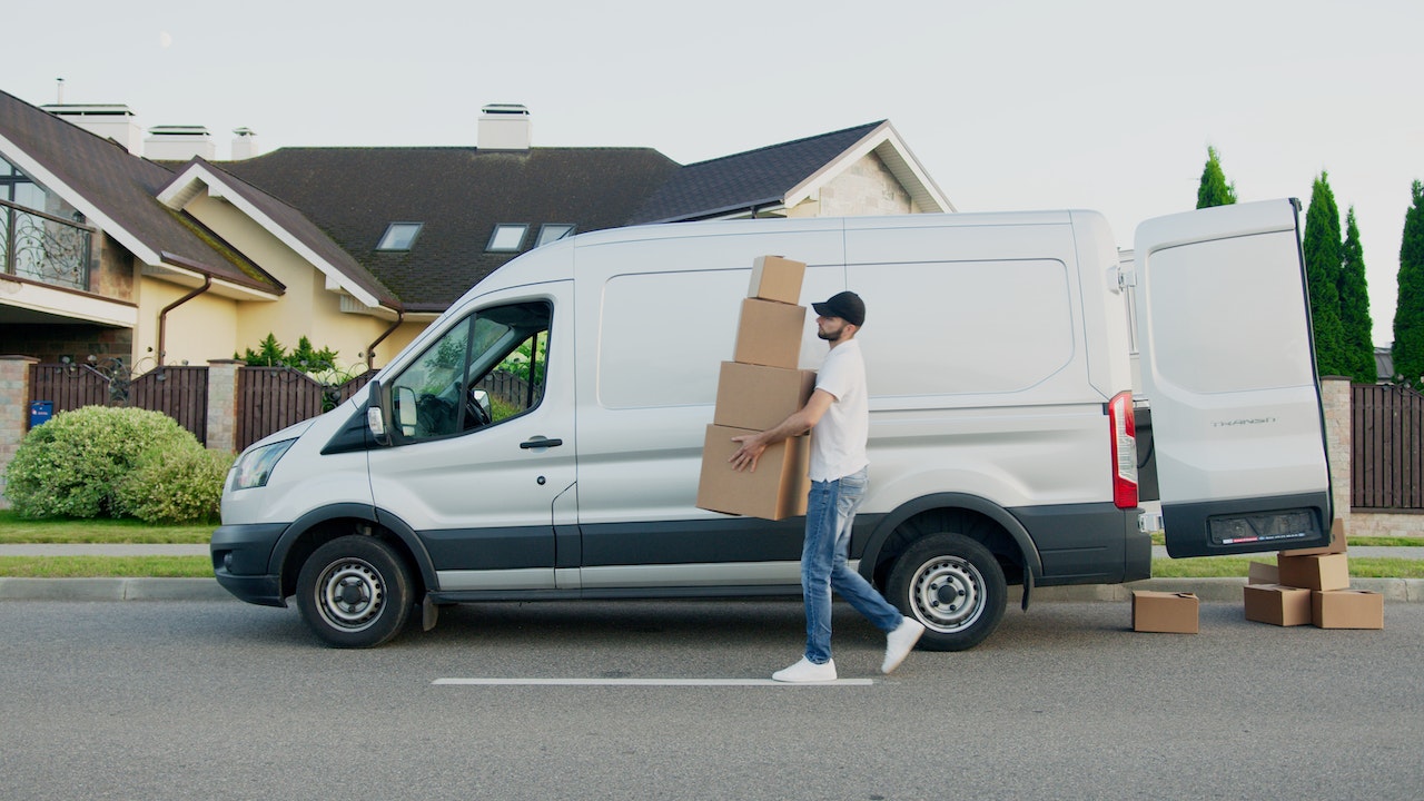 a mover next to a van holding moving boxes