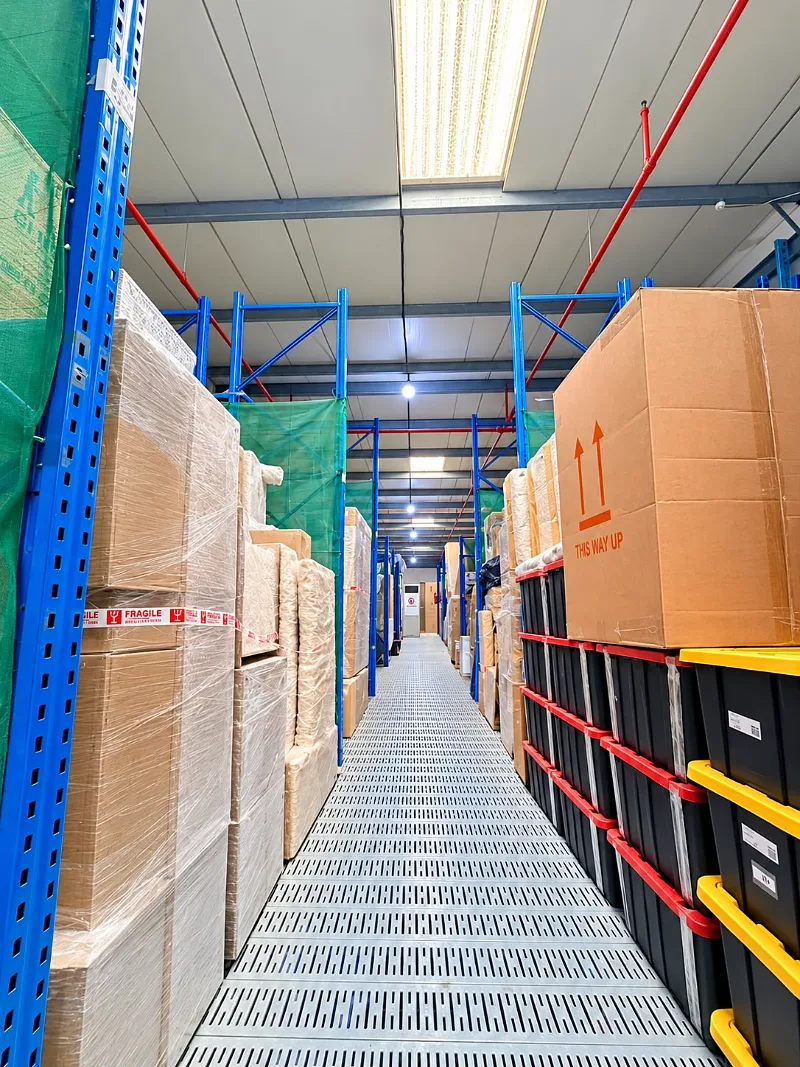 Wrapped furniture and labelled boxes on designated racks in the GI Movers storage warehouse